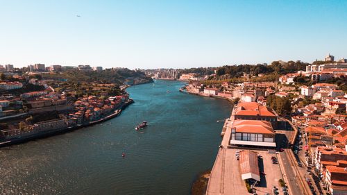 Free Stunning aerial view of the Douro River curving through the vibrant cityscape of Porto under a clear blue sky. Stock Photo