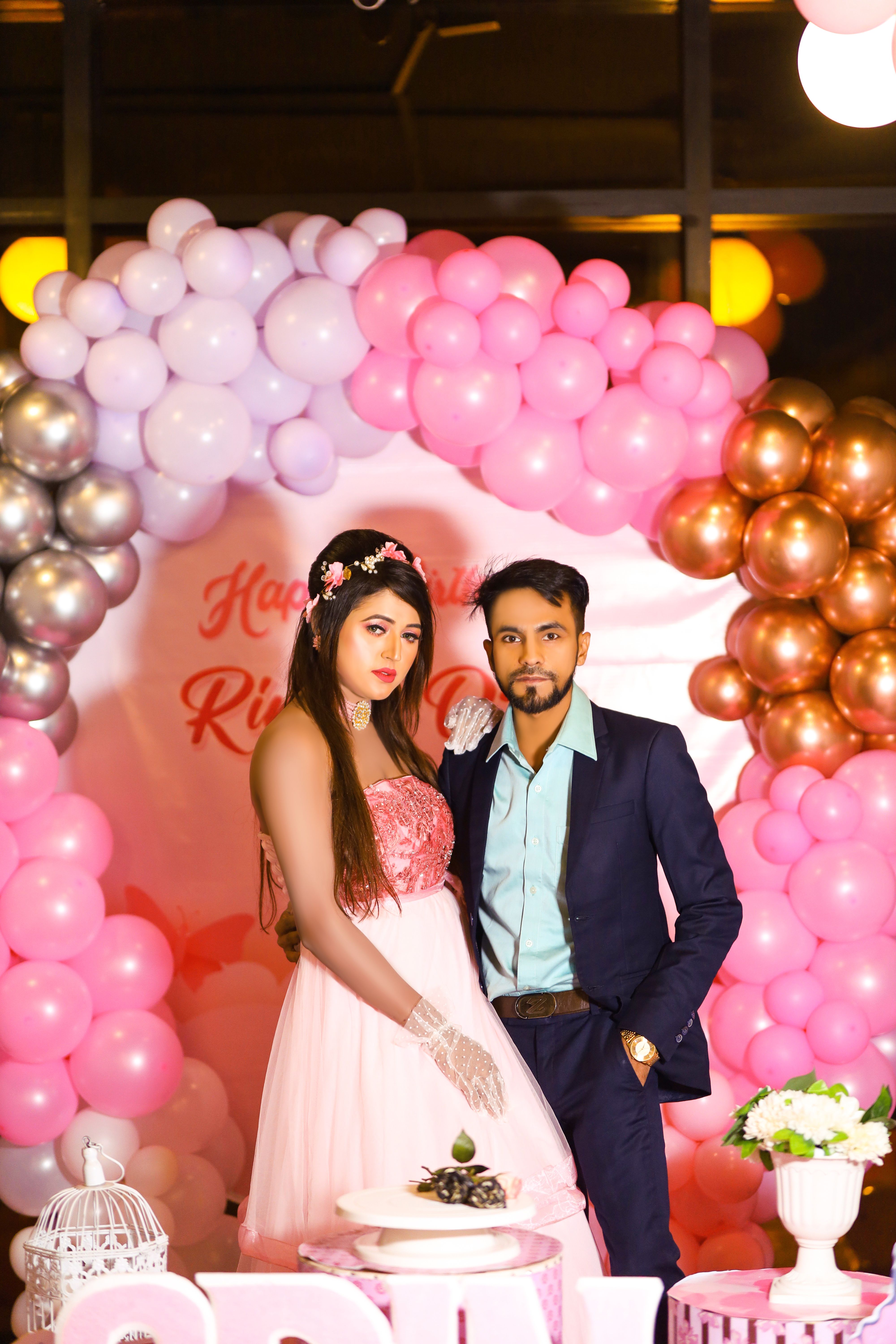 A newlywed couple poses gracefully amidst vibrant balloon decorations at their wedding celebration.