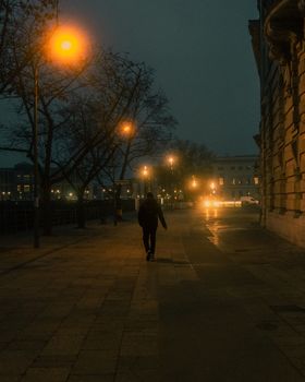 A solitary figure walks under Berlin streetlights on a misty night.