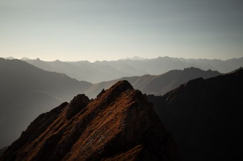 Free Silhouetted view of a mountain range at dawn with layers of mist and sunlight. Stock Photo