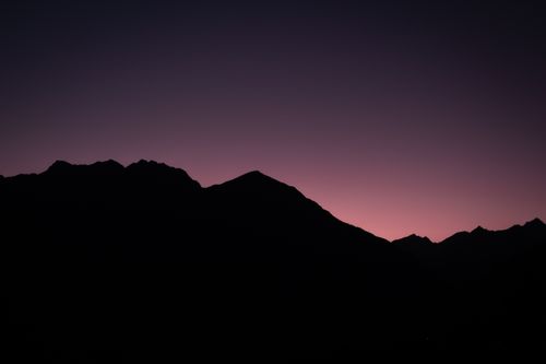 Free A stunning silhouette of Austrian mountains under a purple twilight sky. Captures serene nature. Stock Photo