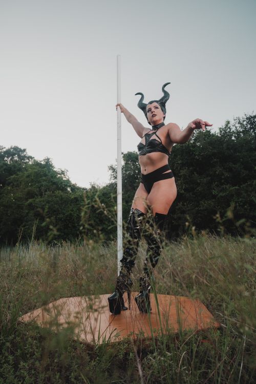Free A person in a costume with horns performs on a pole in a field. Stock Photo