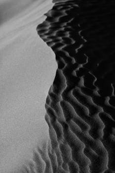 Rippling sand dunes captured in black and white in Kashan, Iran, showcasing natural patterns.