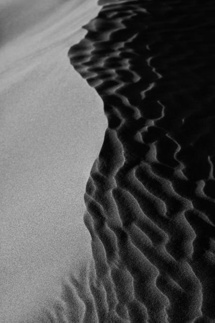 Rippling sand dunes captured in black and white in Kashan, Iran, showcasing natural patterns.