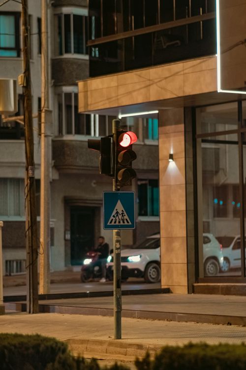 Free City street scene with a red traffic light at night, capturing urban architecture and vehicles. Stock Photo