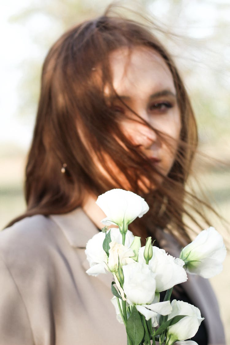 Young Woman Standing Outside And Holding Flowers