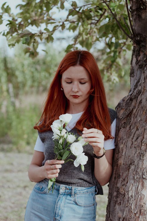 Woman Standing with Flowers by Tree