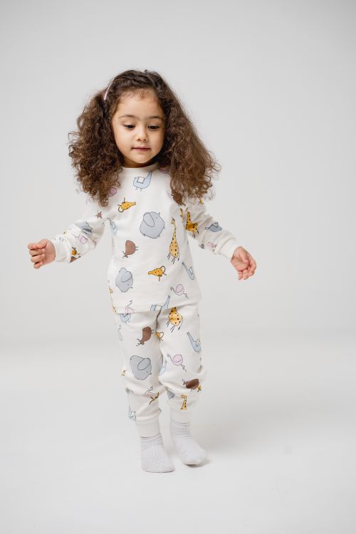 Free Cute young girl with curly hair in pajamas, standing against a white backdrop. Stock Photo