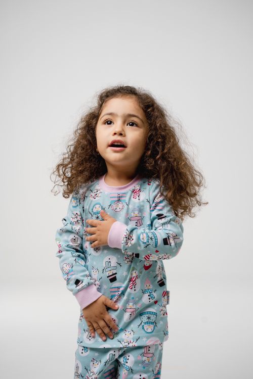 Free Young girl with curly hair wearing cute pajamas against white background. Stock Photo