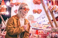 一位戴着太阳镜的快乐女子，正在探索丰富多彩的糖果市场，享受着充满活力的棒棒糖精选