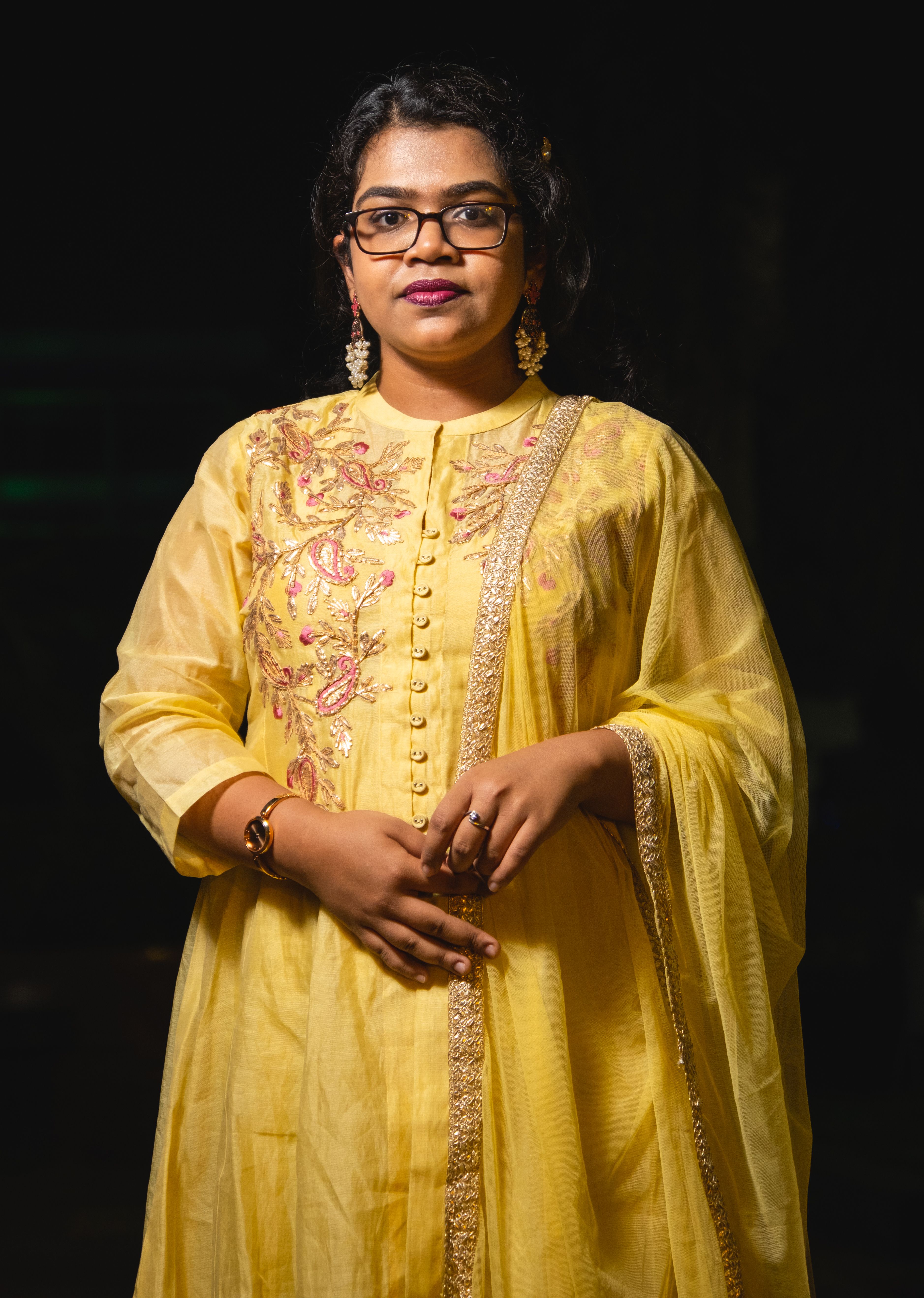 Woman in a traditional yellow gown with embroidery, exuding elegance and charm.