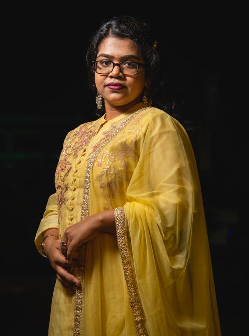 Free A sophisticated woman in embroidered yellow traditional clothing, posing gracefully indoors. Stock Photo