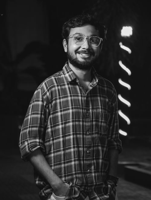 Free Black and white portrait of a smiling man wearing glasses and a checkered shirt at night. Stock Photo