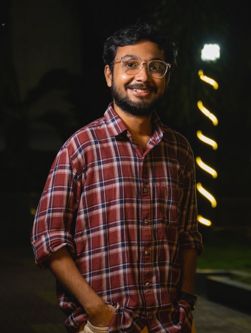 Free Smiling man with eyeglasses in checkered shirt standing outdoors at night. Stock Photo