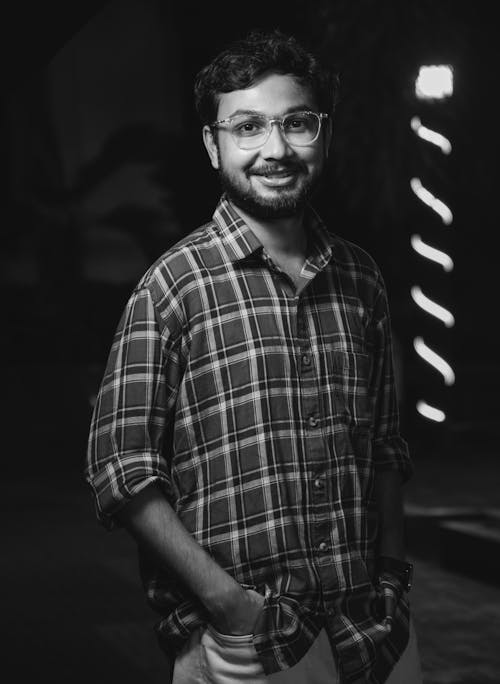 Man in a Checkered Shirt and Eyeglasses Standing and Smiling 