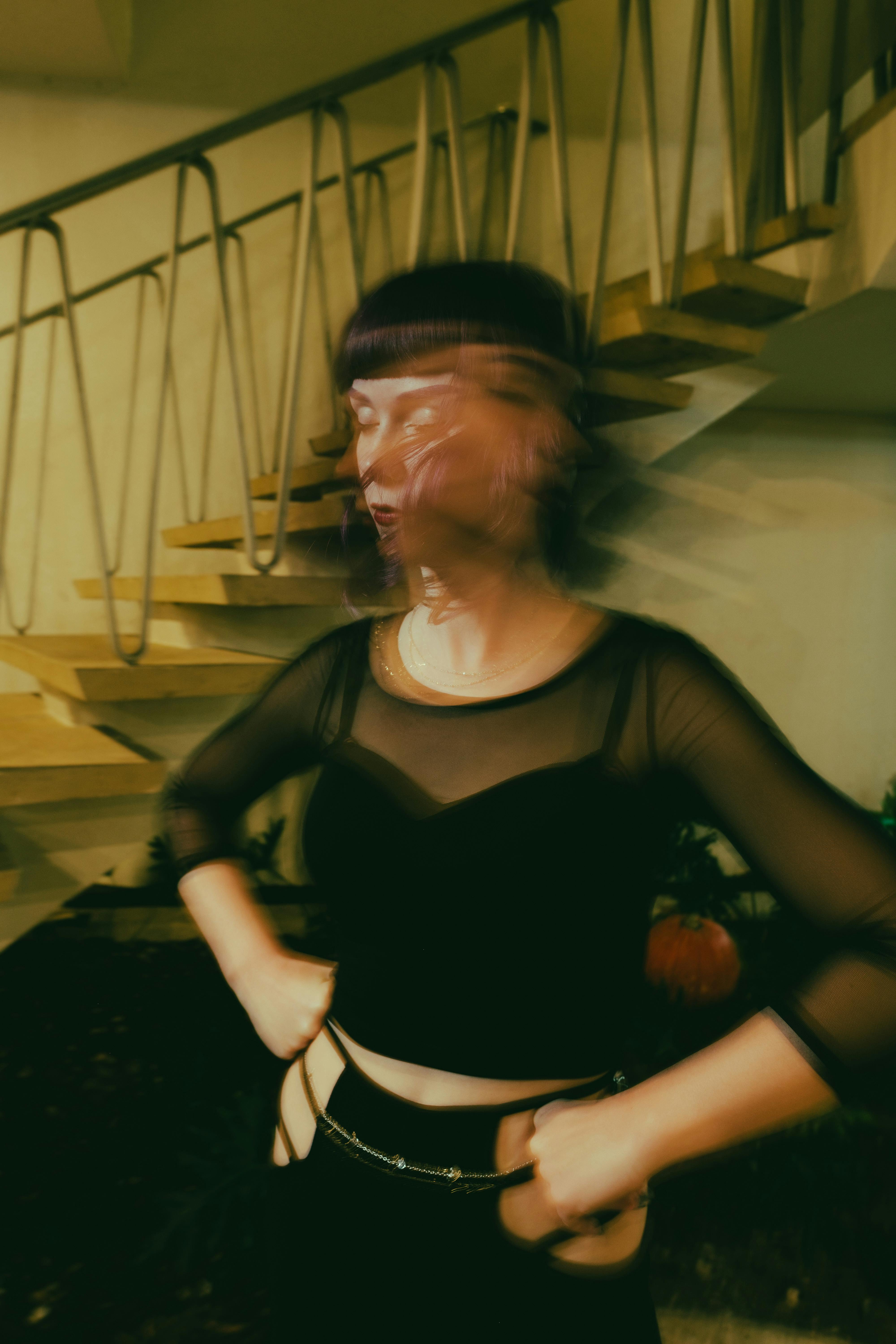 Artistic blurred motion photo of a woman near a staircase indoors.
