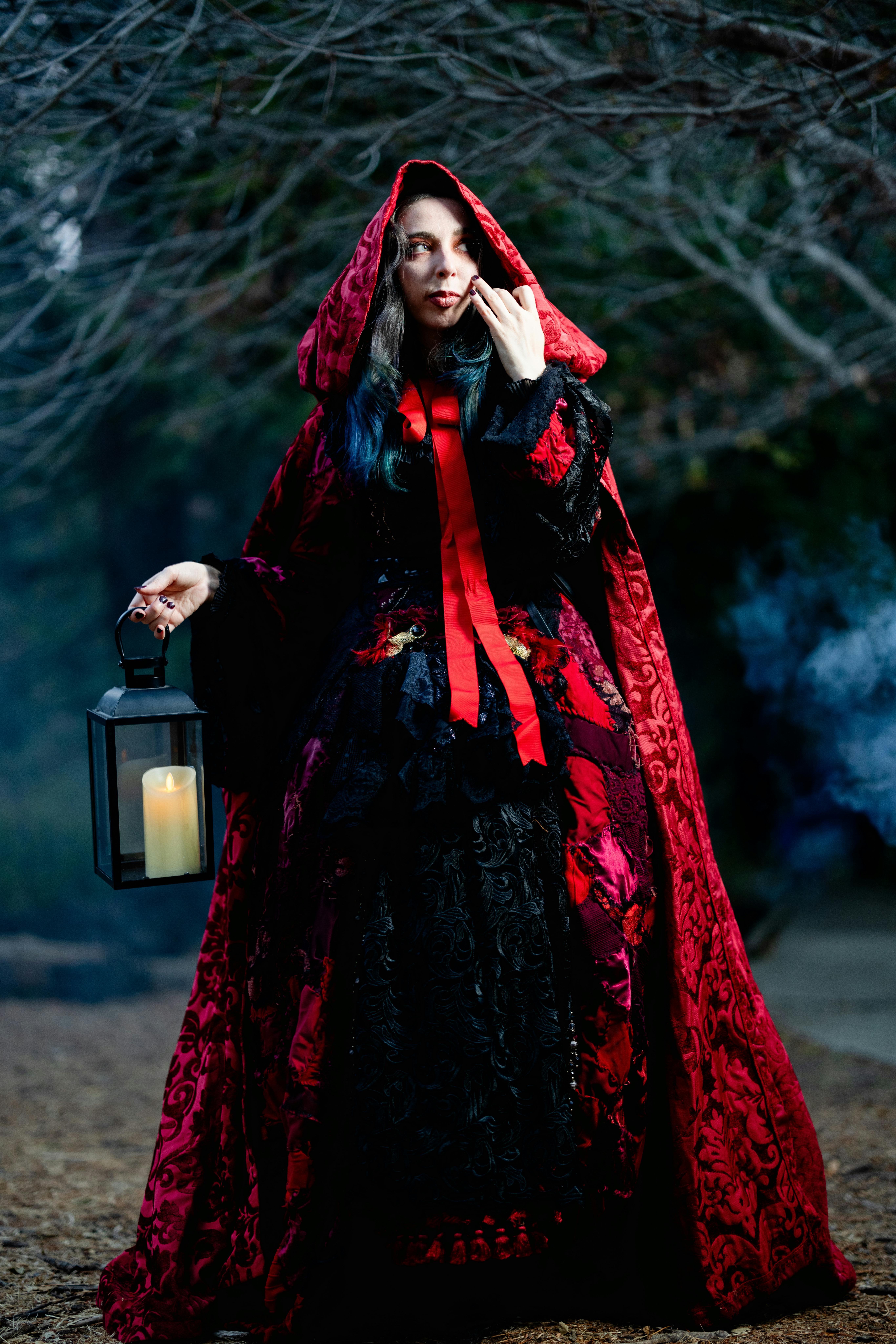 Woman in Halloween Costume with Red Cape Holding a Lantern with Candle