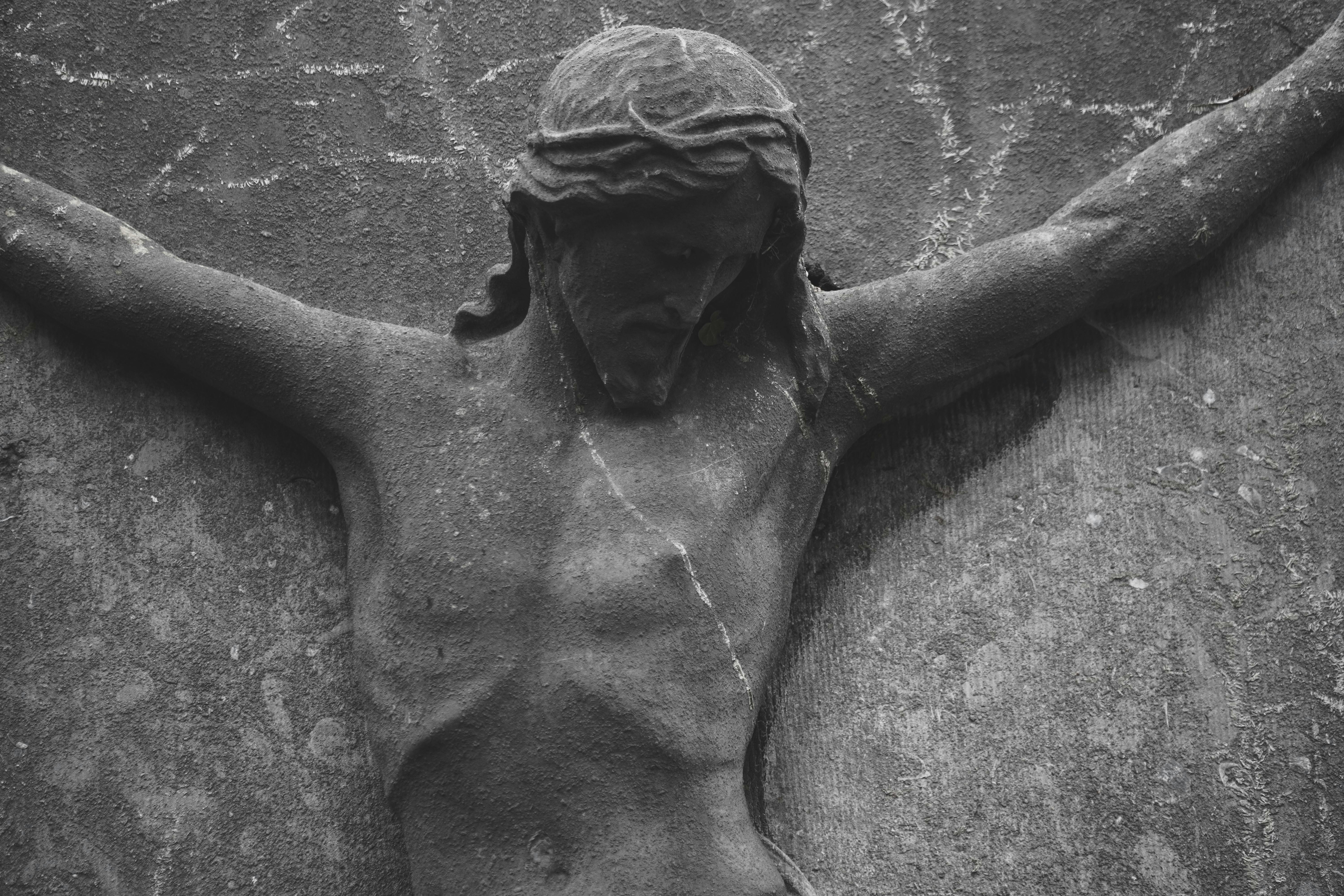 Close-up of an ancient stone sculpture depicting Jesus Christ crucified.