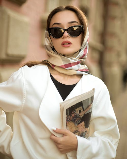 Woman in Sunglasses and a Headscarf Holding a Newspaper