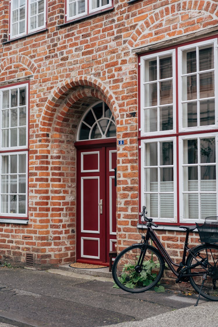 Facade Of A Red Brick Building With A Bicycle In The Front 