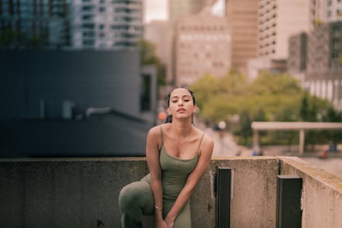 Young Woman in Sportswear Standing on a Balcony with the View of the Street 