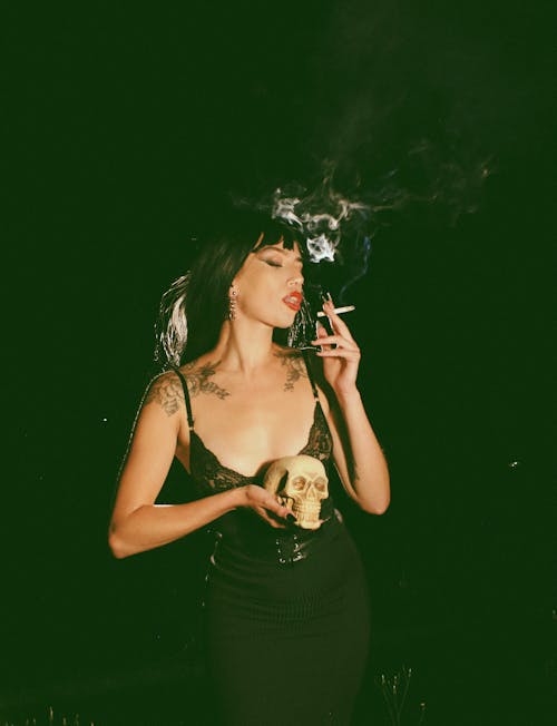 Woman Standing and Holding Skull and Smoking Cigarette