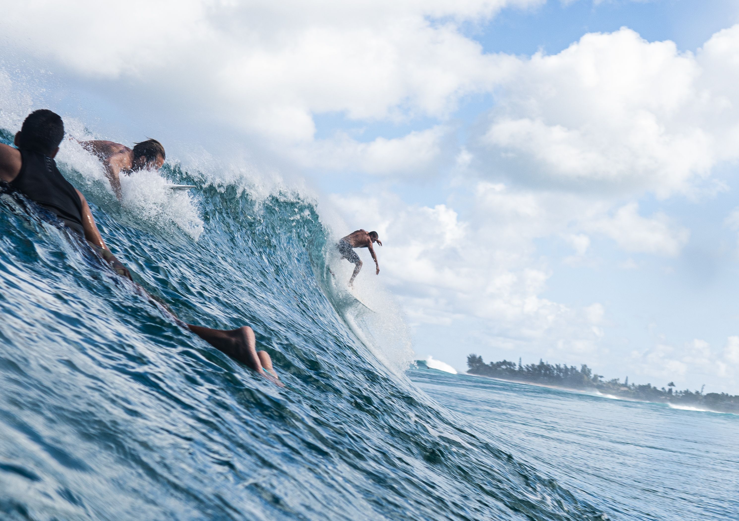 Thrilling surfing scene with multiple surfers riding ocean waves under a bright blue sky.
