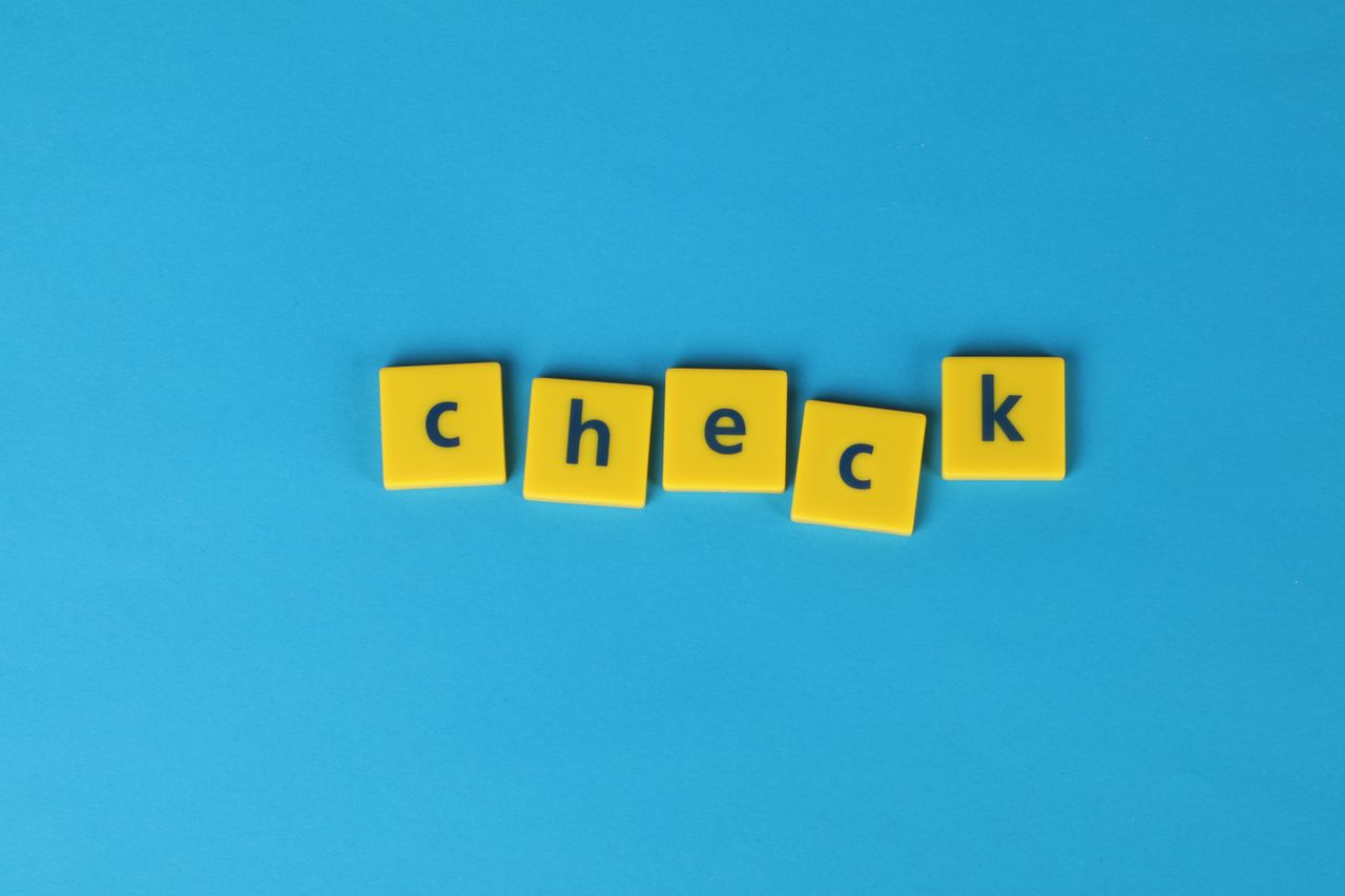 yellow letter tiles spelling check on a vibrant blue background convey