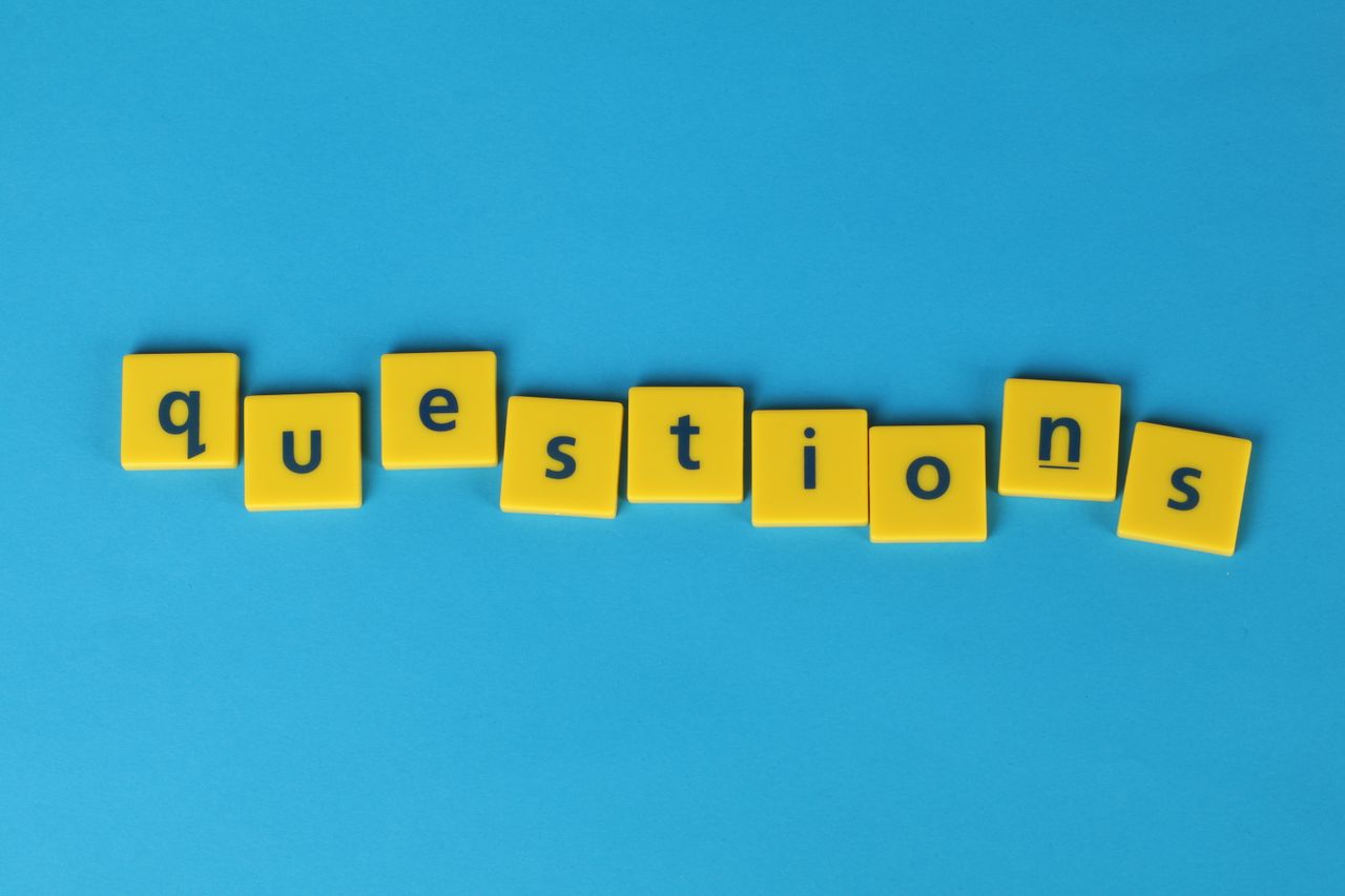yellow letter tiles spell questions on a contrasting blue background