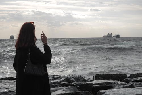 Back View of Woman with Bag Standing on Sea Shore