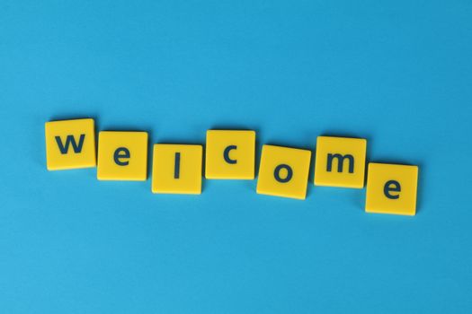 Yellow tiles spelling 'welcome' on a blue background, perfect for greetings.