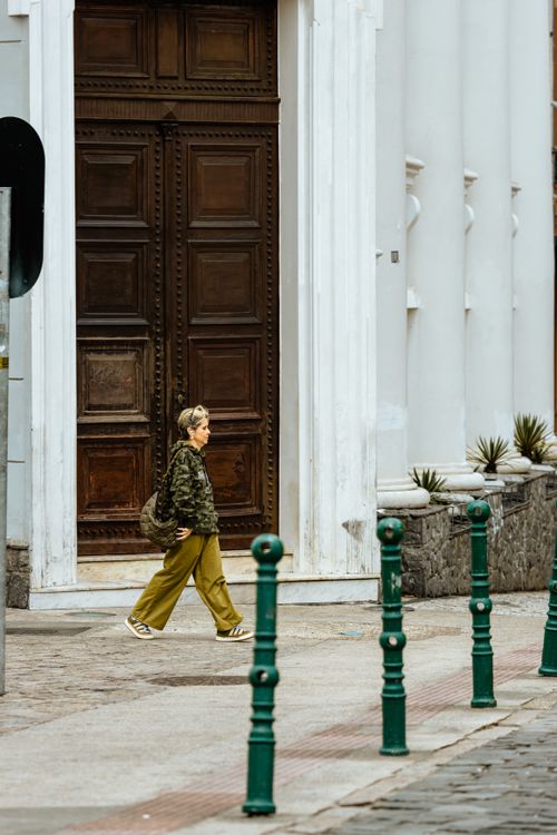 Free A woman walks past a historic city doorway, capturing urban life and architecture. Stock Photo
