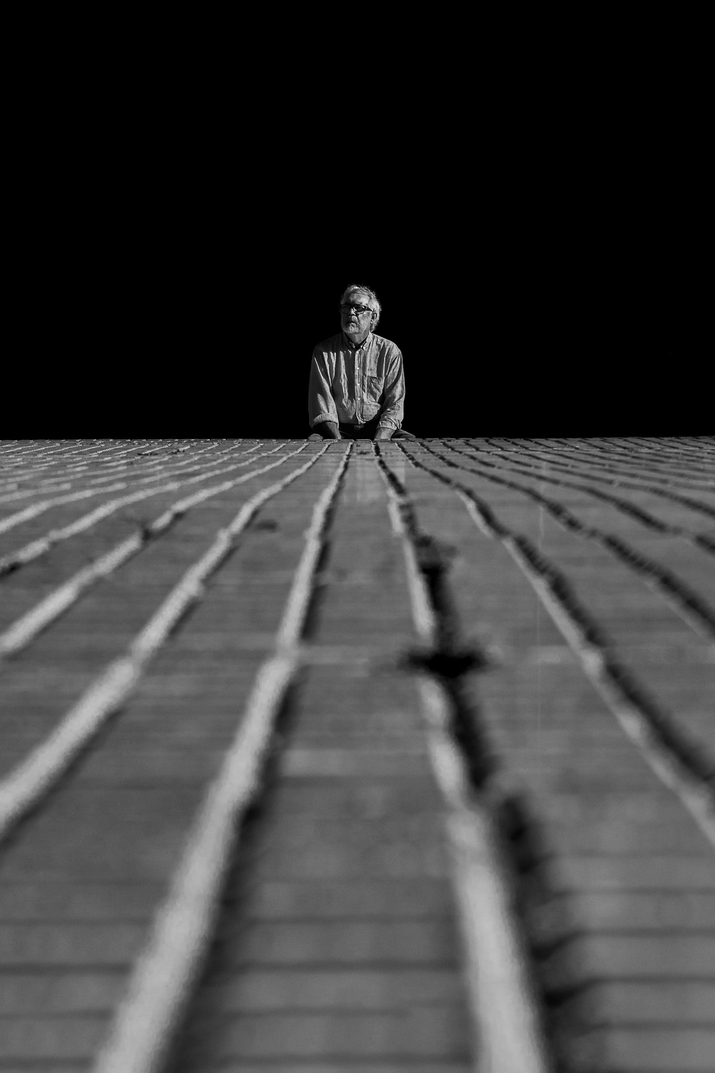 A solitary man sits on a rooftop in Buenos Aires under a dark sky.
