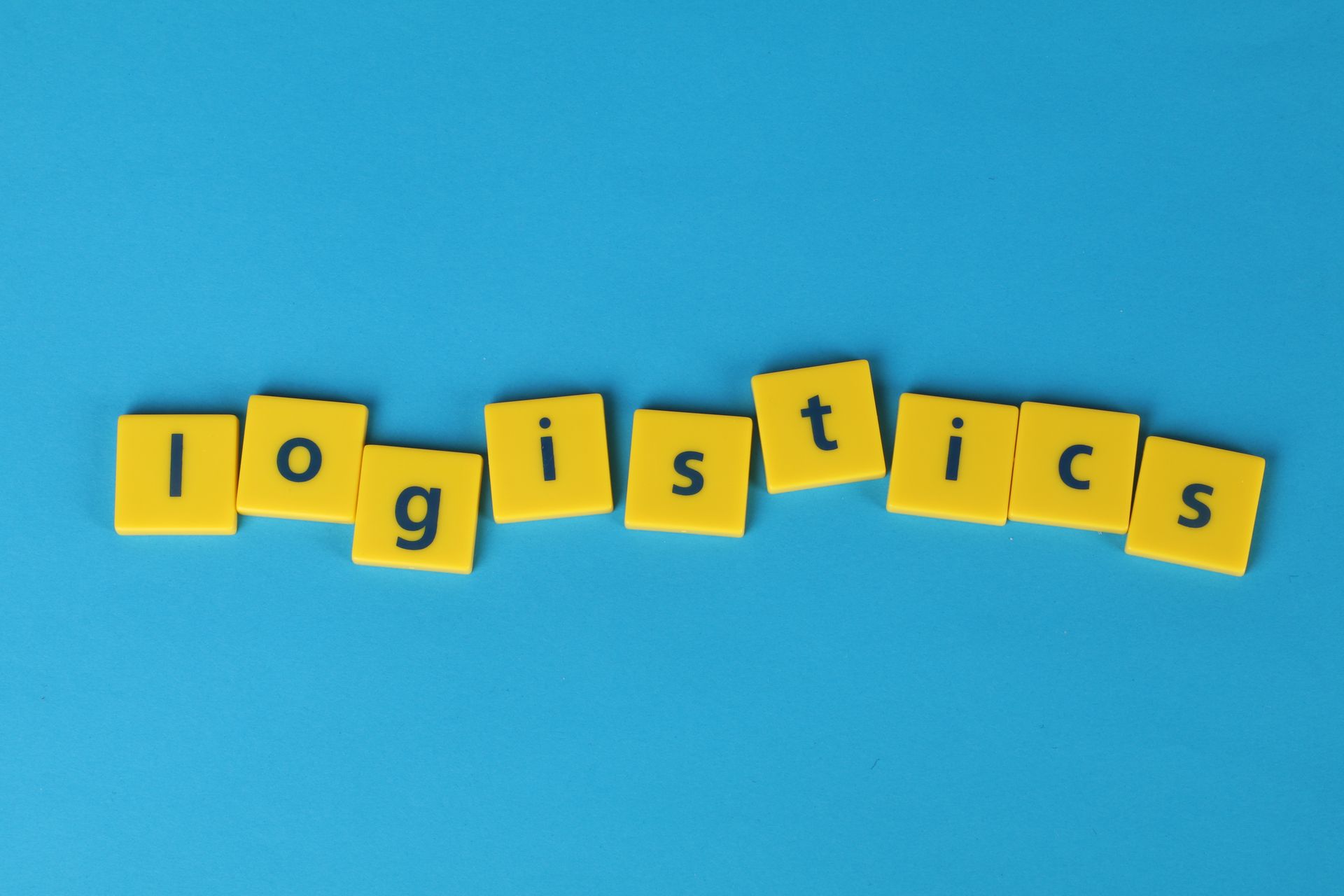 Yellow letter tiles spelling 'logistics' on a vibrant blue background, ideal for business and logistics themes.