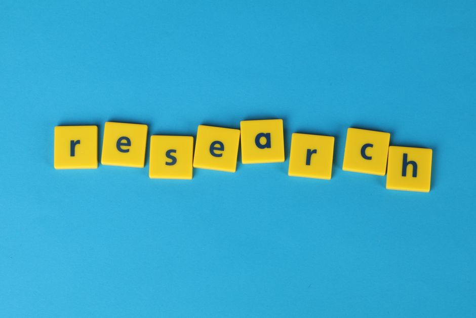 Yellow letter tiles spell the word 'research' on a vibrant blue surface, perfect for educational themes.