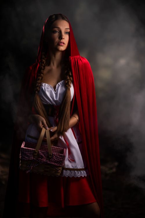 Free Mystical studio portrait of a woman in a Red Riding Hood costume, holding a basket. Stock Photo