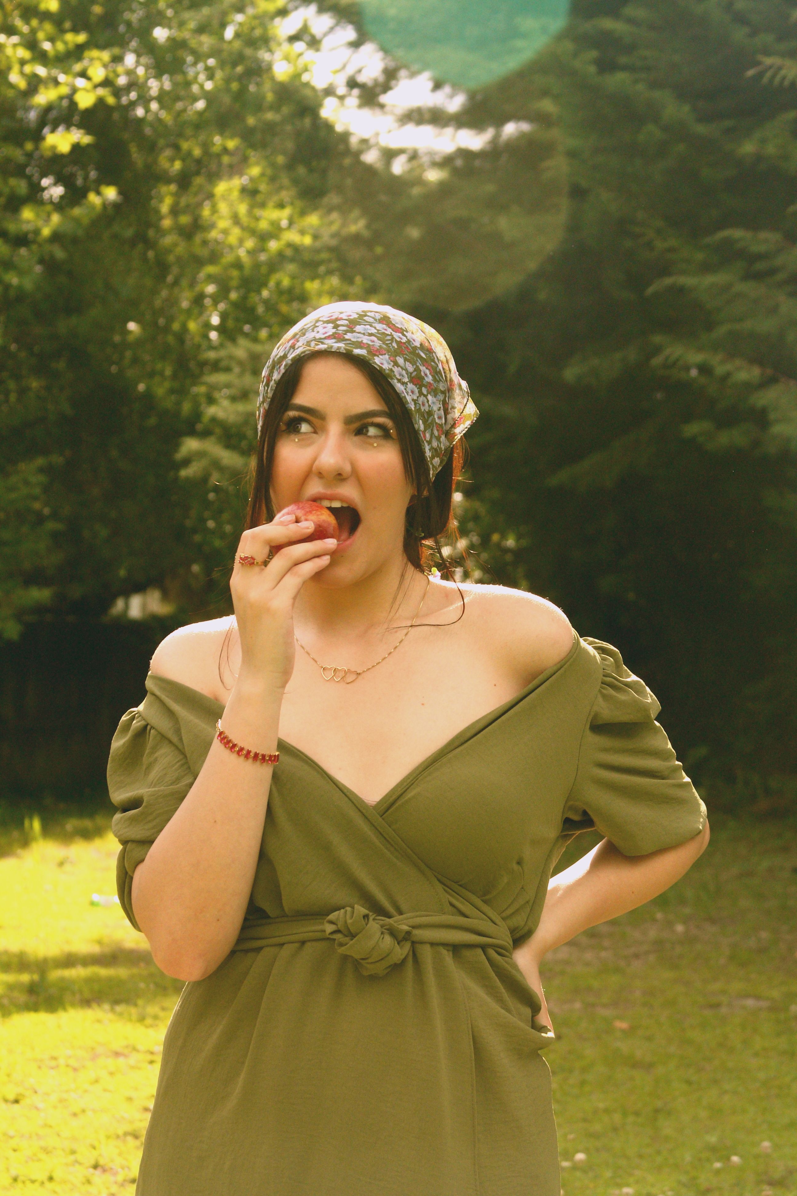 Woman in Olive Green Dress and Floral Pattern Headscarf Eating an Apple   Free Stock Photo
