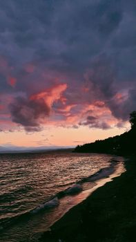 A captivating view of a dramatic sunset with vivid clouds over a tranquil seashore.