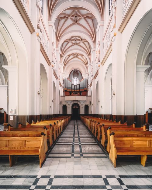 Free Explore the majestic architecture of a Catholic church in Trzebinia, Poland, with its intricate arches and empty wooden benches. Stock Photo