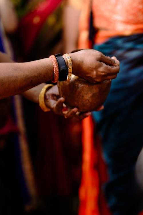 Hands with Bracelets Holding Traditional Container