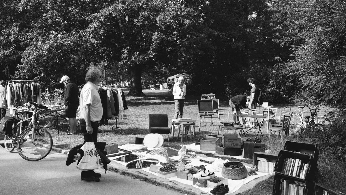 Pessoas examinando produtos usados expostos em uma feira de garagem ao ar livre