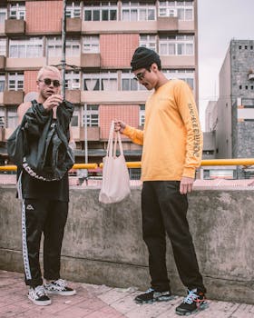 Two men in urban casual outfits and sunglasses on a city street.