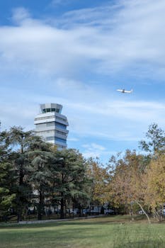 Airplane soaring through clear blue sky past Istanbul airport control tower. Scenic and serene.