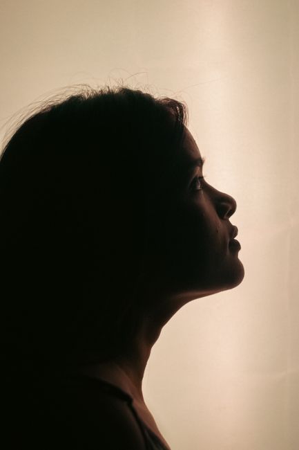 Silhouette portrait of a young woman with serene expression against a minimalistic background.