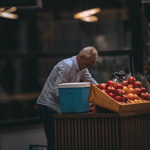 Elderly Merchant Working at Stall with Fruits at Market