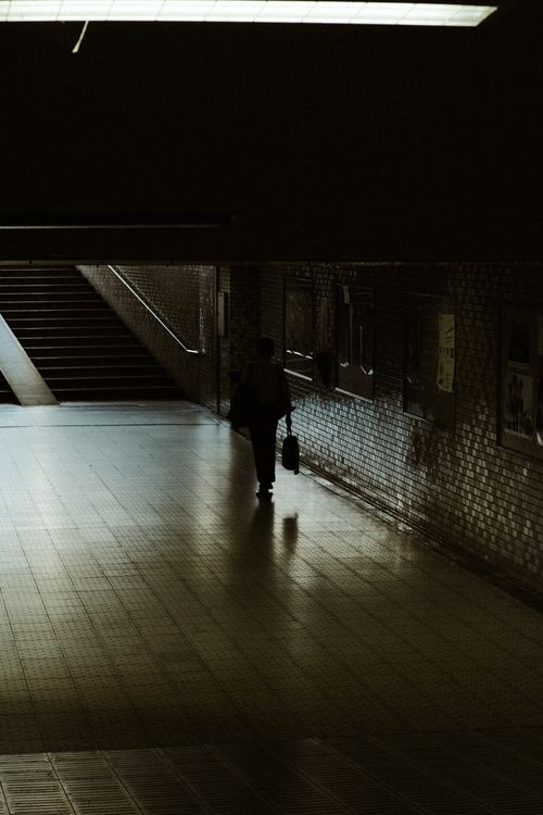 Free Silhouette of a lone pedestrian walking through a dim urban tunnel, creating a moody and mysterious ambiance. Stock Photo