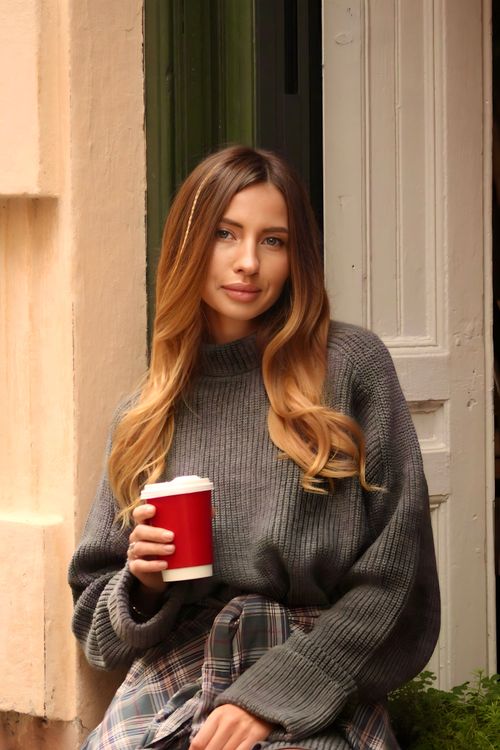 Free Young woman relaxing with a coffee outdoors in casual attire. Stock Photo