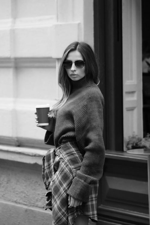 Free Fashionable woman holding a coffee cup, wearing sunglasses and a sweater. Stock Photo