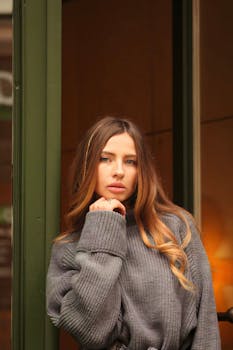 A fashionable woman poses indoors wearing a cozy oversized sweater, exuding style and confidence.