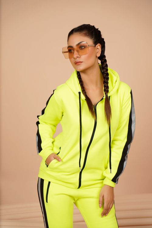 Free Trendy young woman posing confidently in a neon tracksuit, showcasing modern fashion. Stock Photo